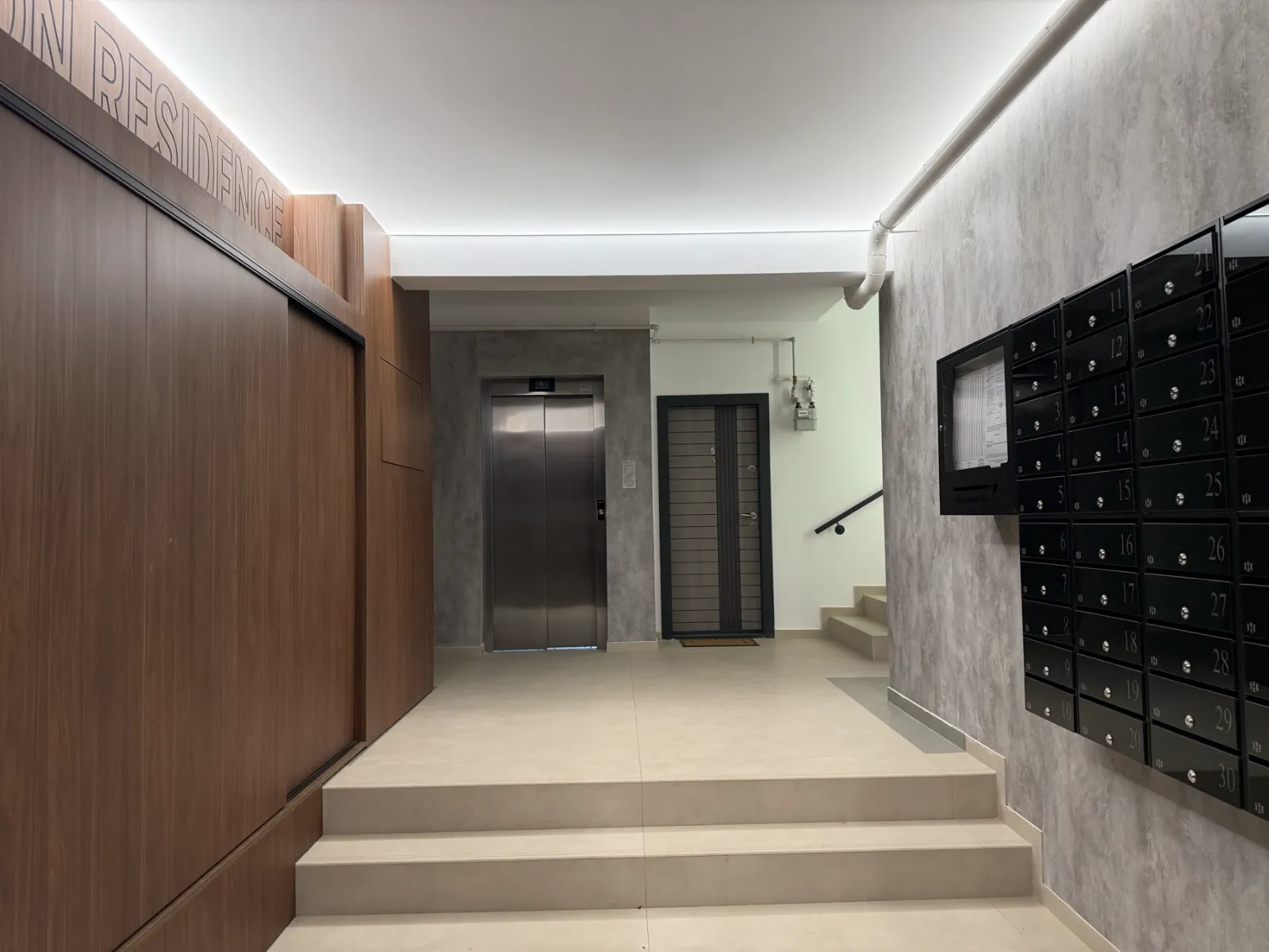 Holul de intrare Hamilton Residence — finisaje din lemn, lift și branding iluminat